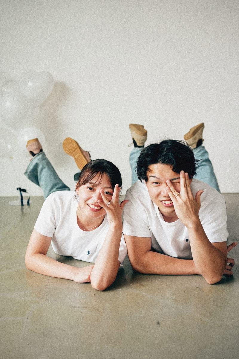 床に寝転がって指ハートをするご夫婦